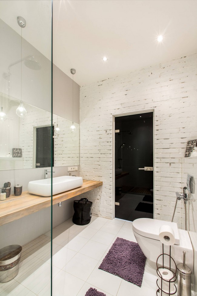 Совмещенный санузел в современном стиле с душевой вместо ванны. Примечателен здесь выбор отделки: на одной стене сохранена открытая кирпичная кладка