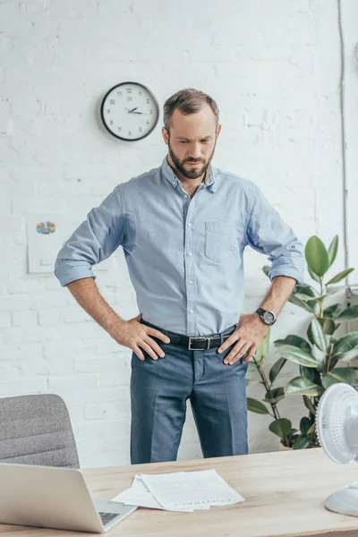 Sweaty Businessman Wet Shirt Standing Office Laptop Documents Electric Fan — стоковое фото